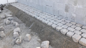 Pose de pavés anciens en ligne à joints croisés par un tâcheron